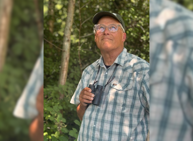 A photo of Jay Inslee with binoculars in a forest. 
