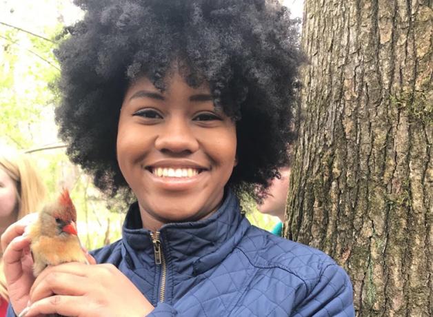 Sheridan Alford, smiling at the camera while holding a female Cardinal in her hands