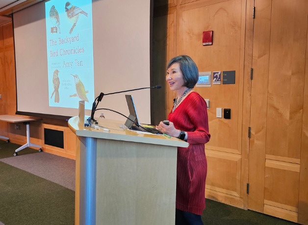 A photo of Amy Tan standing at a podium presenting a seminar about her book The Backyard Bird Chronicles.