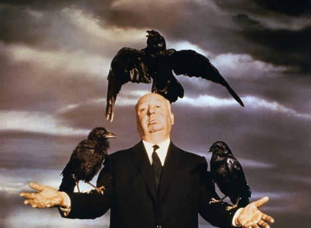 Alfred Hitchcock posing with crows on his arms