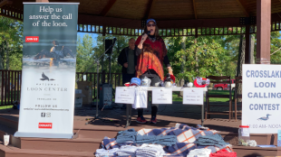 A loon calling competition contestant performs on a gazebo