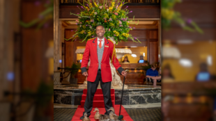 Kenon Walker stands on a red carpet with five ducks at his feet 