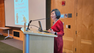 A photo of Amy Tan standing at a podium presenting a seminar about her book The Backyard Bird Chronicles.