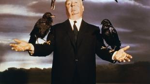 Alfred Hitchcock posing with crows on his arms